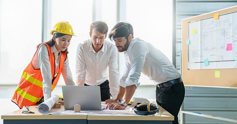 Construction-estimator-works-with-engineers-in-office-in-front-of-open-laptop.jpeg